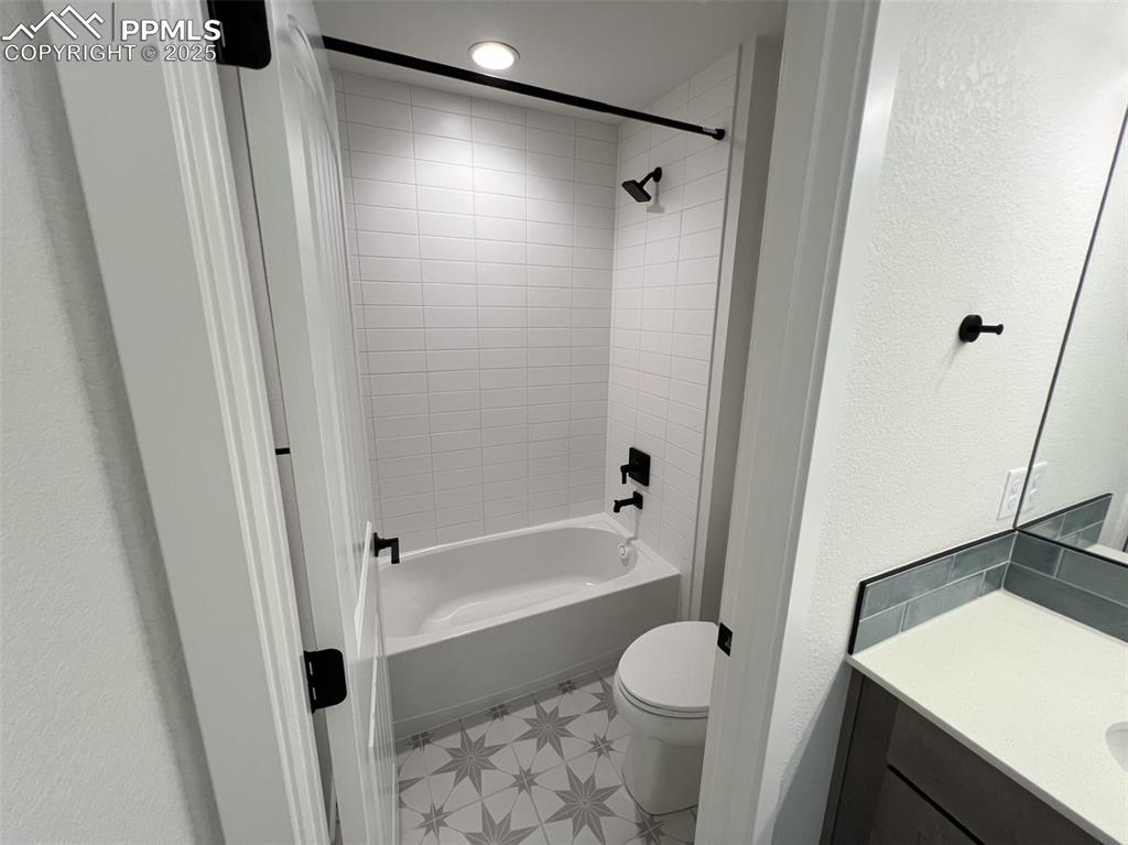Image 14 of 17: Full bathroom featuring a textured wall, vanity, and shower / bath combinat