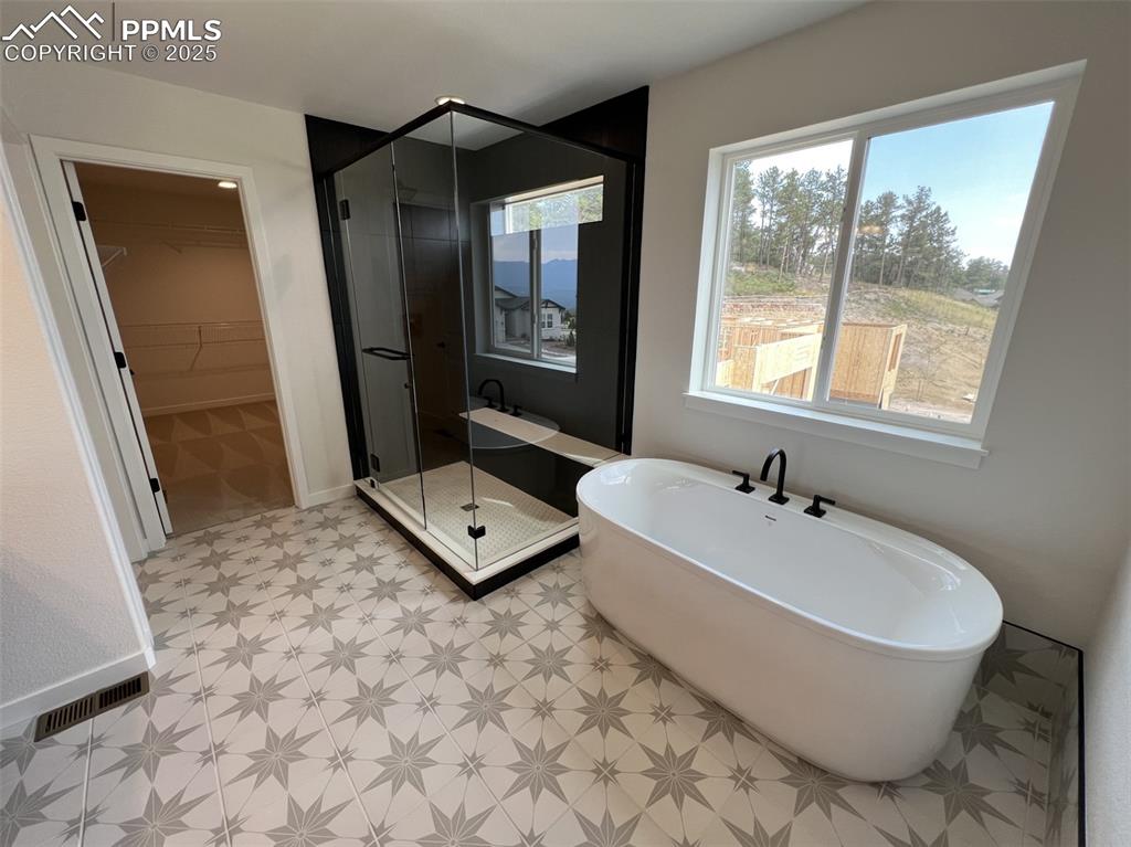 Image 9 of 17: Bathroom with a huge walk in closet, a soaking tub, a spa shower stall, and