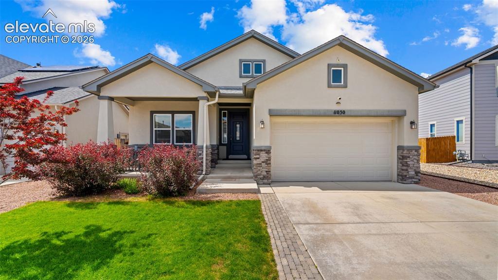Image 1 of 39: Contemporary stucco exterior with a covered entry, stone accents, two-car g