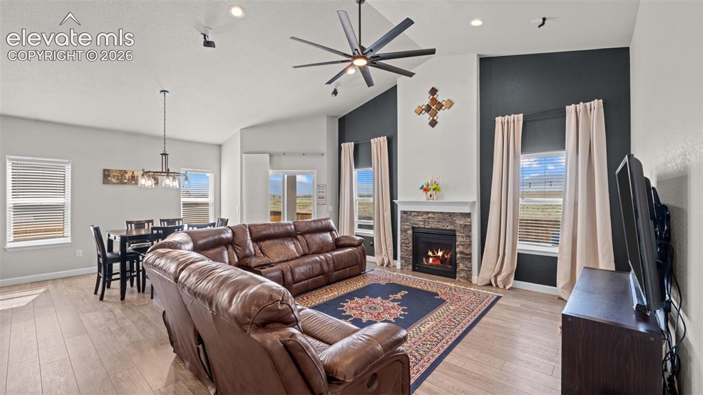 Image 13 of 39: Open-concept living area featuring a vaulted ceiling and wood-finish floori