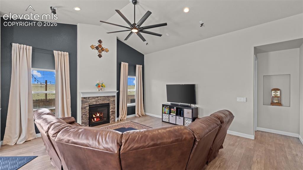 Image 14 of 39: Vaulted ceiling living area featuring wood-finish flooring, a stone-clad fi