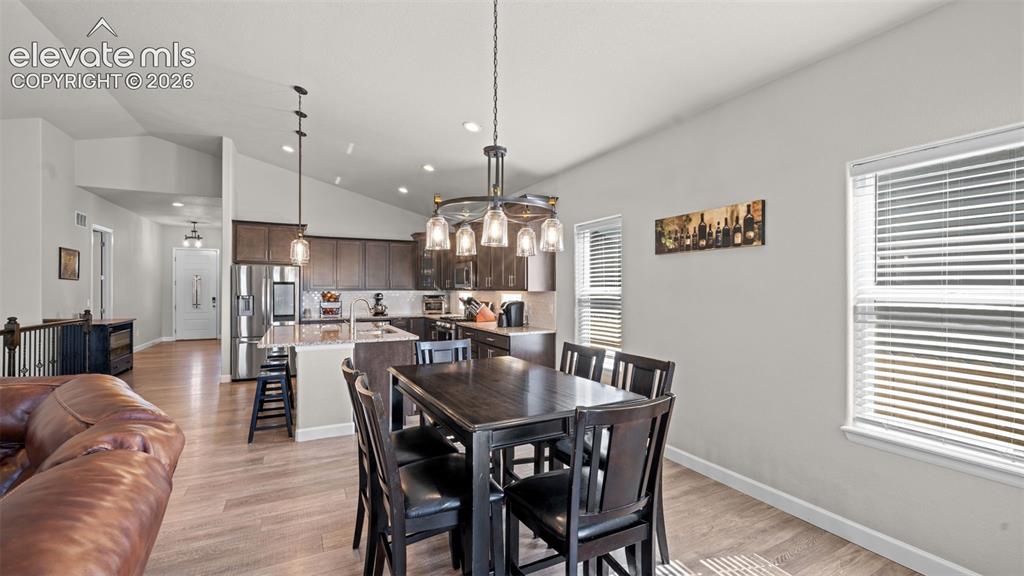 Image 15 of 39: Open-concept living area featuring wood-finish flooring, vaulted ceilings,