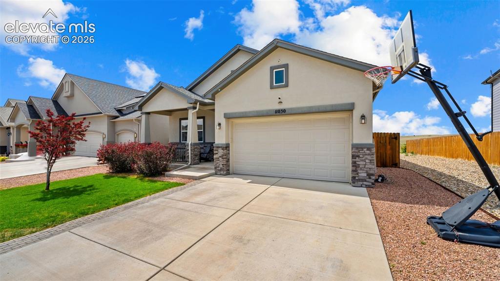 Image 2 of 39: Front exterior featuring a two-car garage, stone accents, and stucco siding