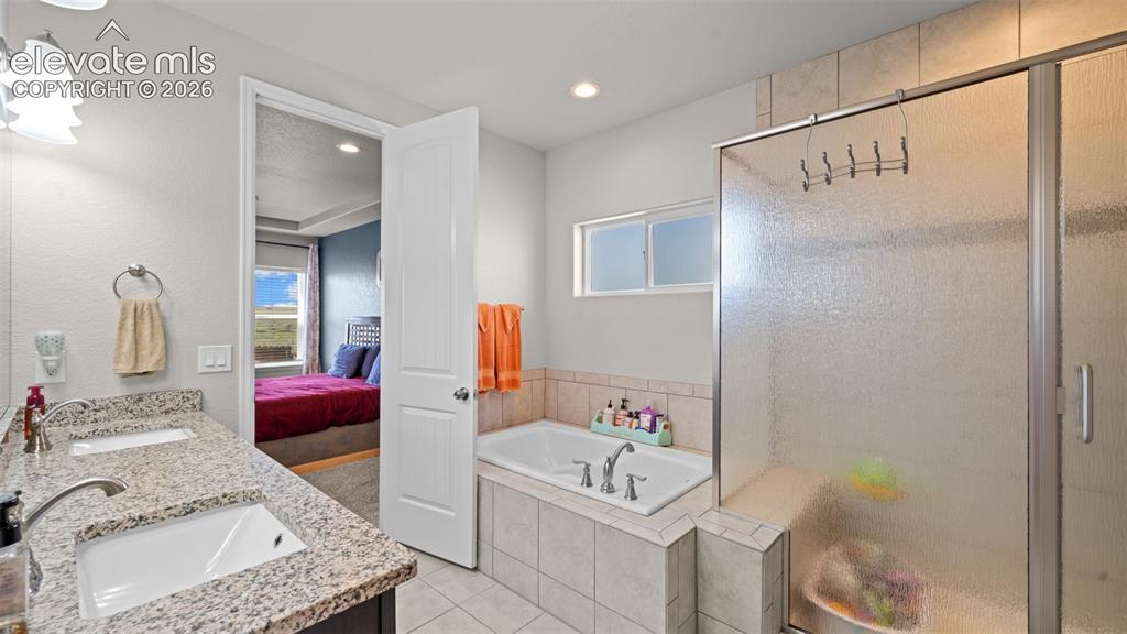 Image 20 of 39: Spacious bathroom featuring a double vanity with stone-finish countertops,