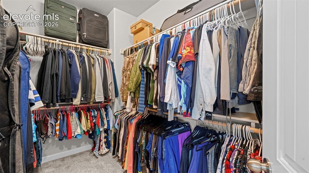 Image 21 of 39: Custom closet organization system featuring multiple hanging rods and integ
