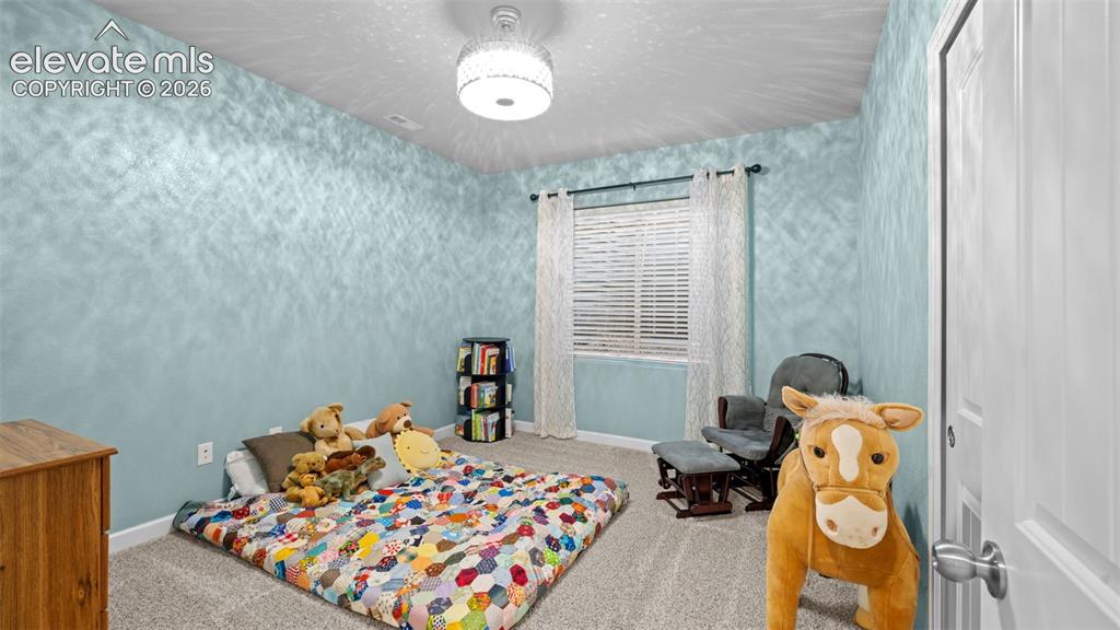 Image 22 of 39: Carpeted room featuring light blue walls with a textured finish, a window w