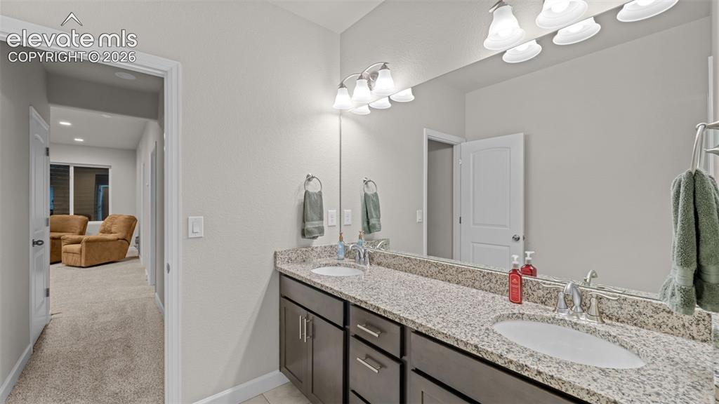 Image 23 of 39: Double vanity with granite-style countertop, dual integrated sinks, and ind