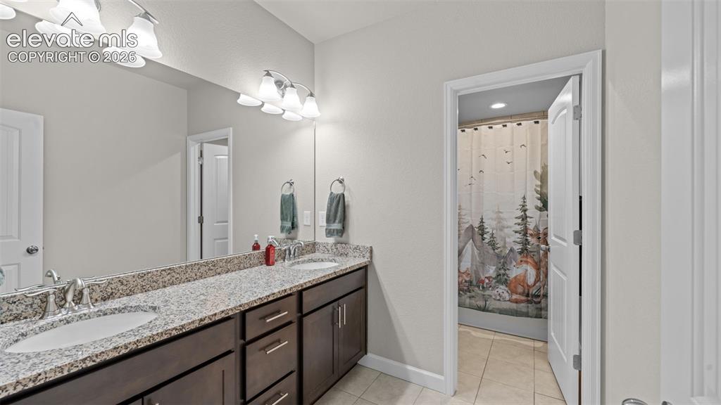 Image 27 of 39: Bathroom featuring a dual vanity with a speckled countertop and integrated