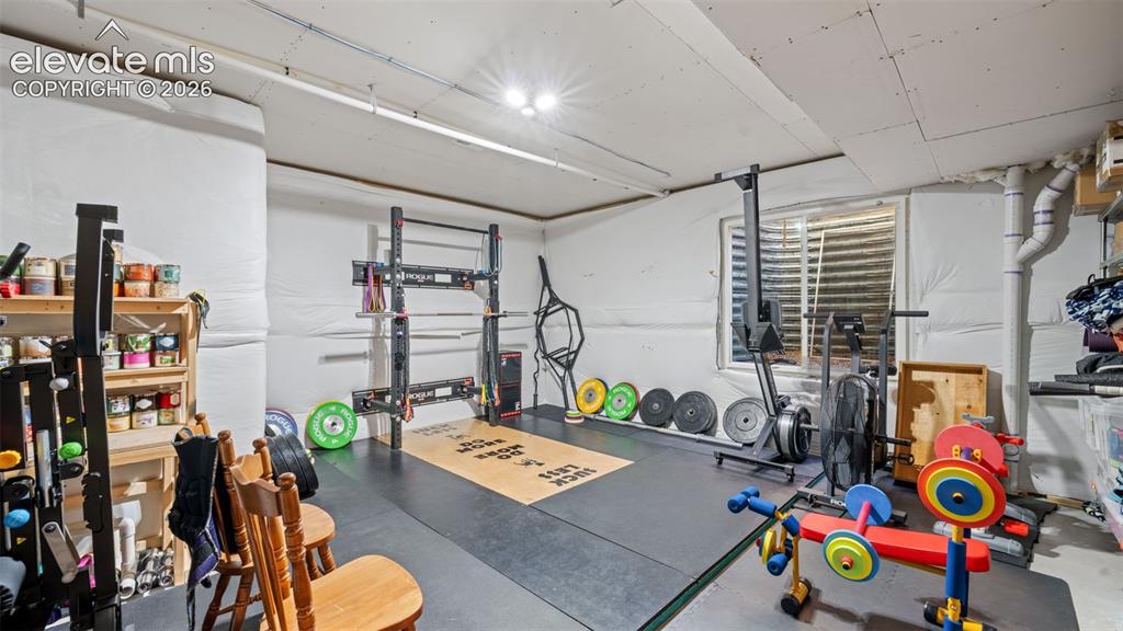 Image 29 of 39: Dedicated fitness area featuring black rubber flooring, a built-in squat ra