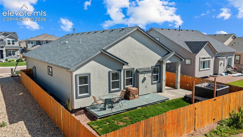 Image 36 of 39: Rear exterior featuring a wood fence, stucco siding, and a gabled roofline