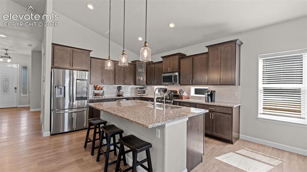 Image 9 of 39: Spacious kitchen featuring an expansive center island with seating, pendant