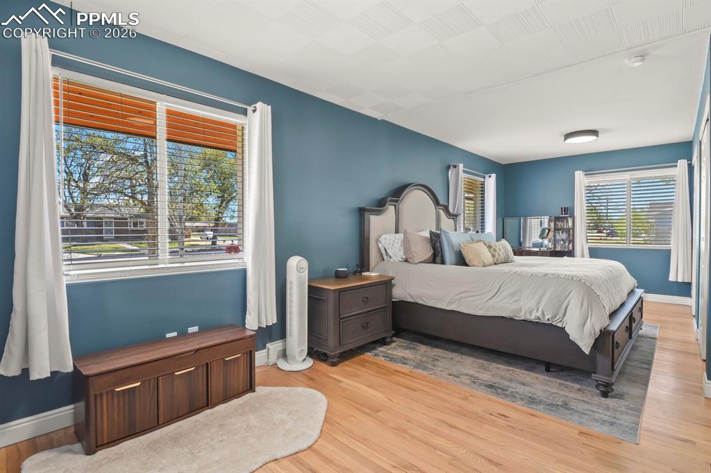 Image 14 of 48: Spacious primary bedroom featuring hardwood flooring, multiple windows with