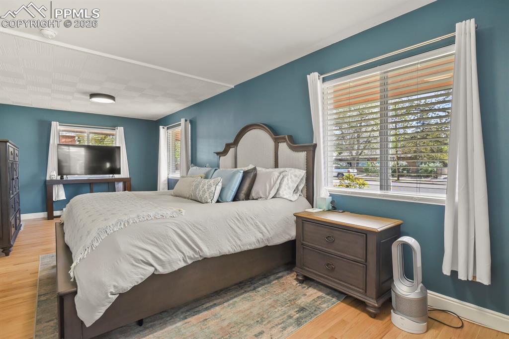 Image 15 of 48: Spacious primary bedroom featuring hardwood flooring and multiple windows
