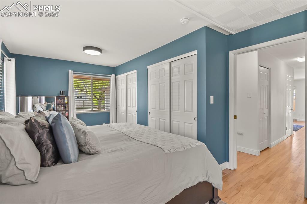 Image 16 of 48: Spacious primary bedroom featuring hardwood flooring, double closets and mu
