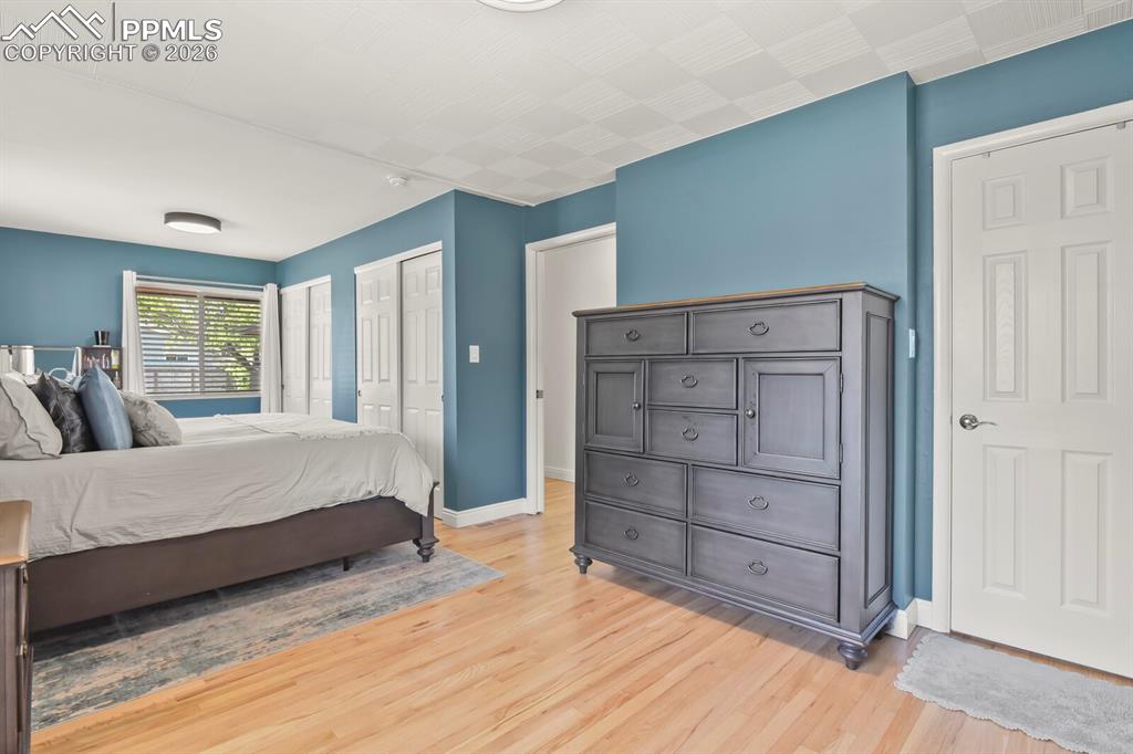 Image 17 of 48: Spacious primary bedroom featuring hardwood flooring, double closets, multi