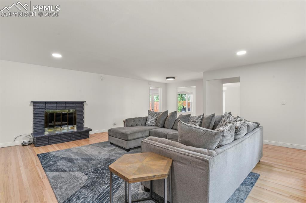 Image 22 of 48: Hardwood flooring complements the  fireplace featuring a dark brick surroun