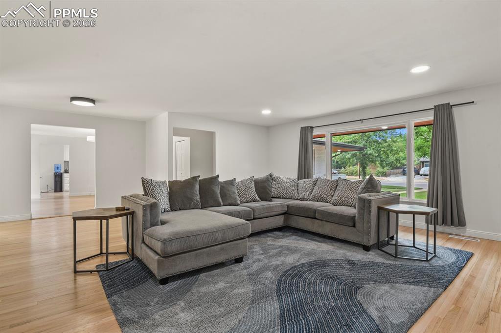 Image 23 of 48: Bright living space featuring hardwood flooring and recessed lighting