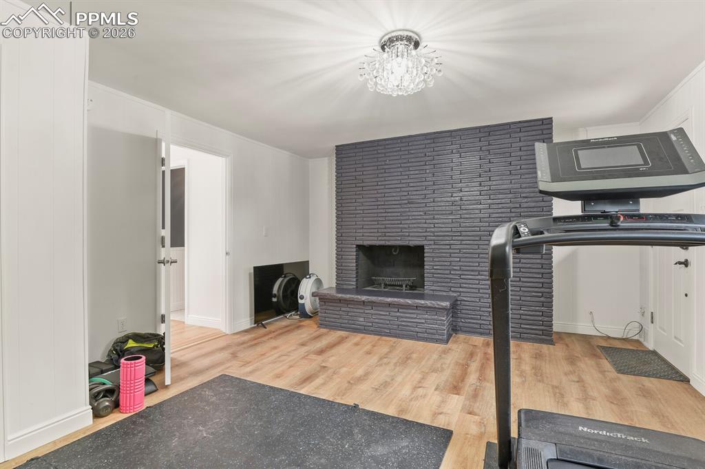 Image 26 of 48: 3rd bedroom on main level with a fireplace, exterior door to outside, hardw