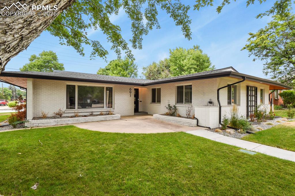 Image 3 of 48: Mid-century modern residence featuring a white brick exterior, dark trim, a