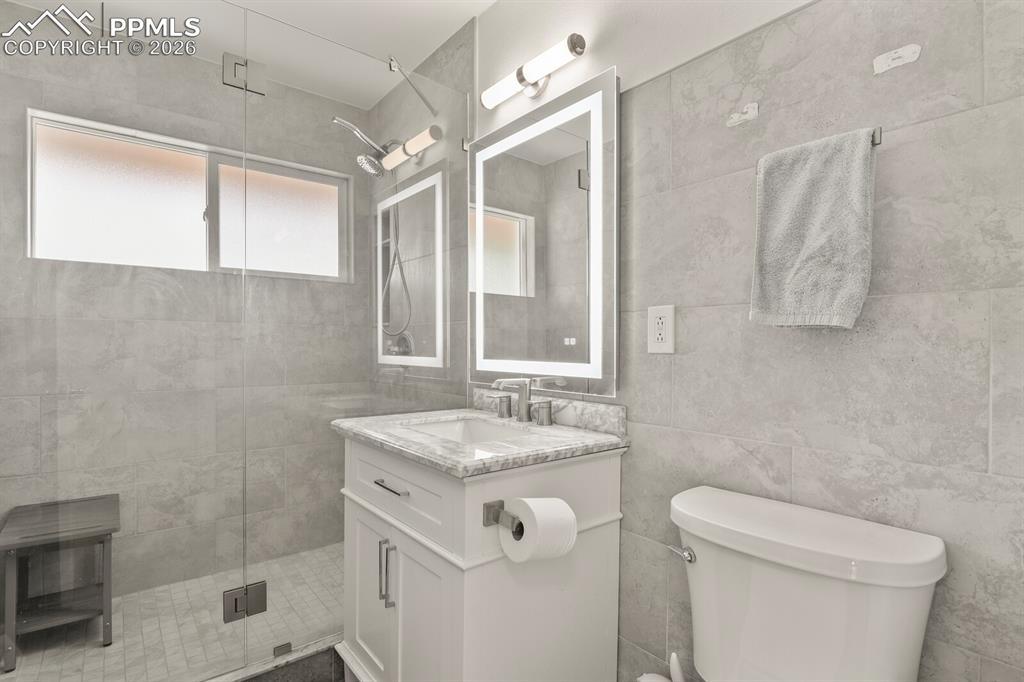Image 30 of 48: Bathroom featuring a frameless glass shower door with dual shower heads