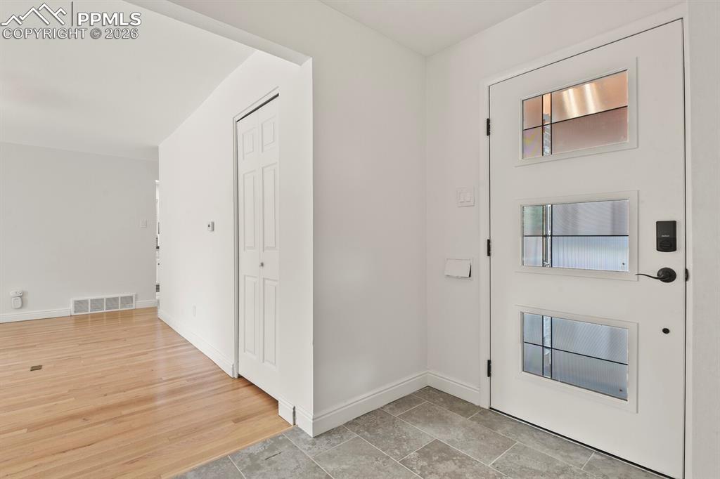 Image 4 of 48: Entryway featuring a white door with three rectangular lites, a black smart