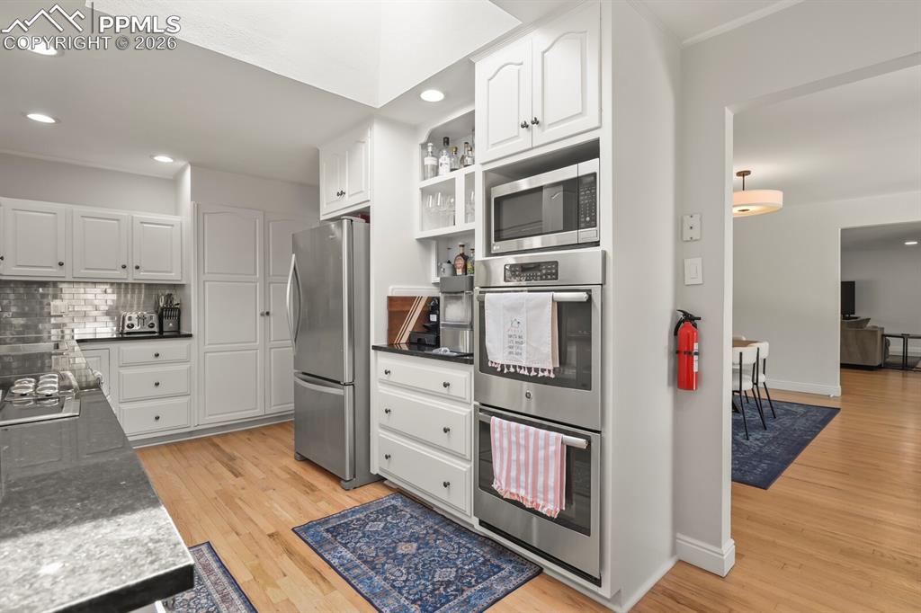 Image 7 of 48: Kitchen featuring hardwood flooring, white cabinetry, stainless steel appli