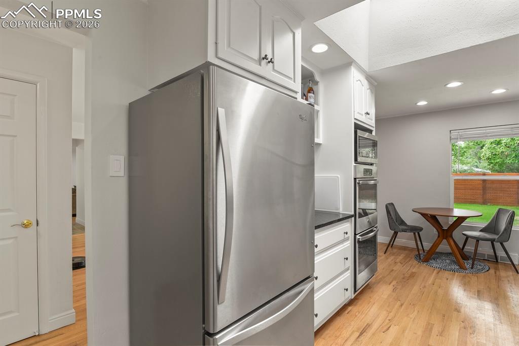 Image 9 of 48: Kitchen featuring a stainless steel refrigerator, white cabinetry and integ
