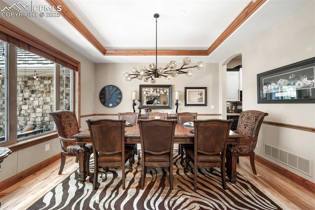 Image 10 of 47: The formal dining room features a lavish chandelier, tray ceiling & hardwoo