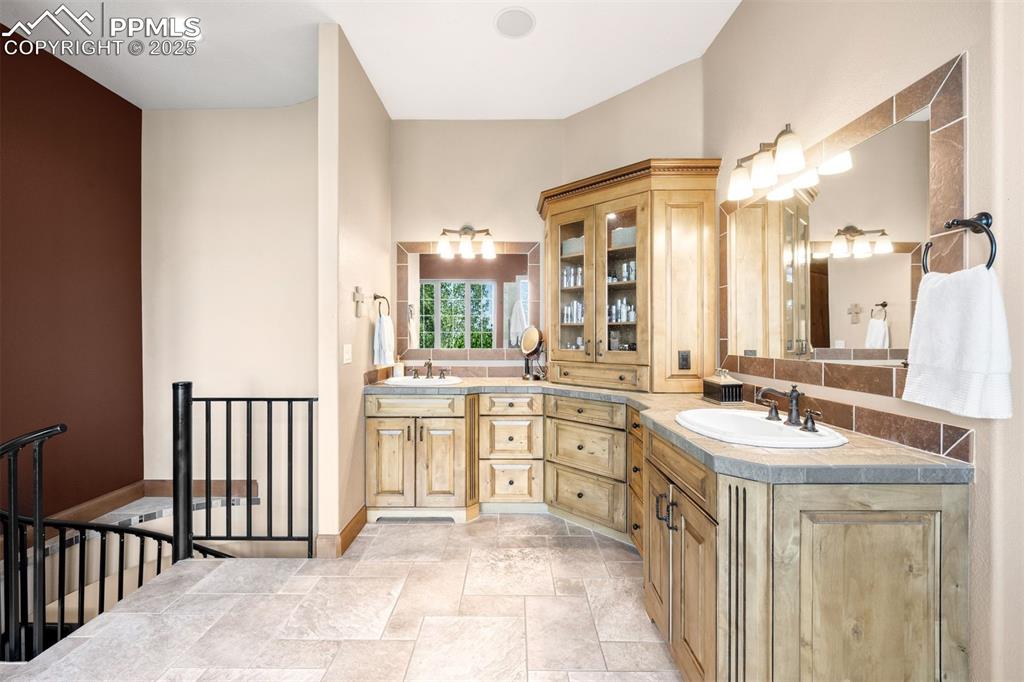 Image 22 of 47: Double sinks, extended vanity & glass door toiletry cupboard offer refined