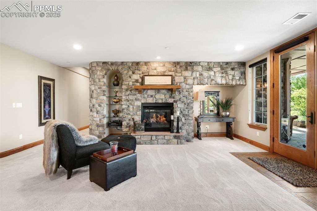 Image 30 of 47: Another cozy corner with stacked stone wall, gas fireplace and garden views
