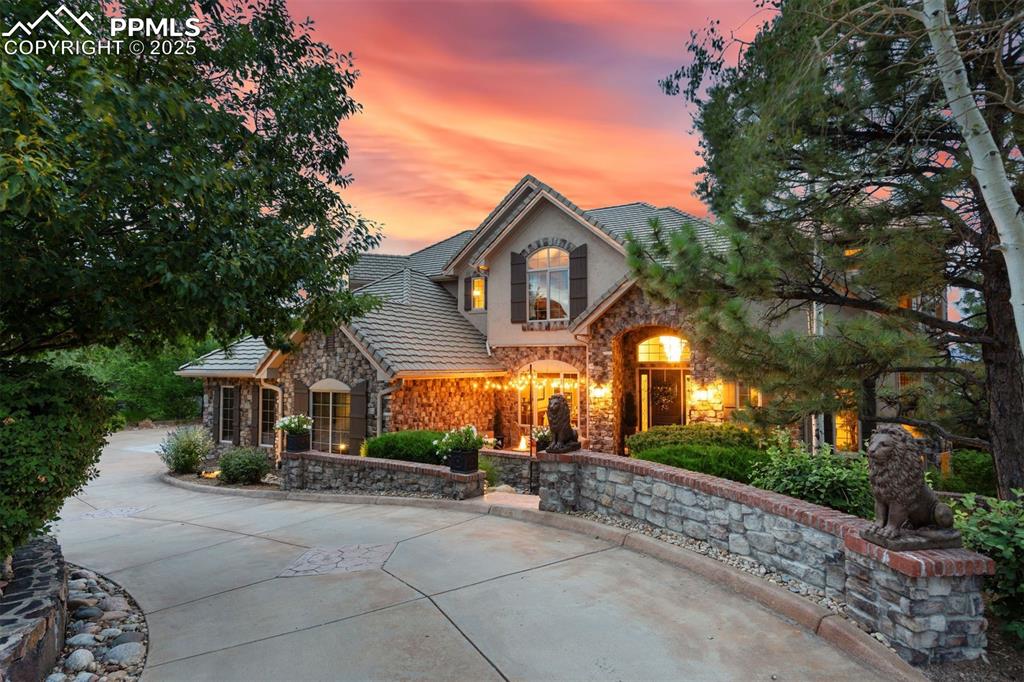 Image 8 of 47: Incomparable curb appeal with warm lighting, a fire pit & the soothing soun