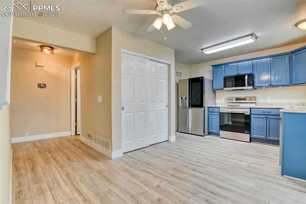 Image 5 of 21: Kitchen with stainless steel appliances, blue cabinetry, light countertops,