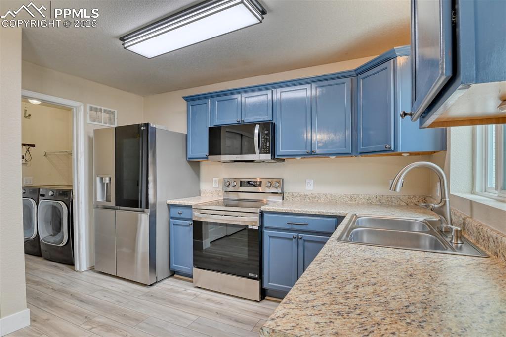 Image 6 of 21: Kitchen featuring appliances with stainless steel finishes, blue cabinetry,