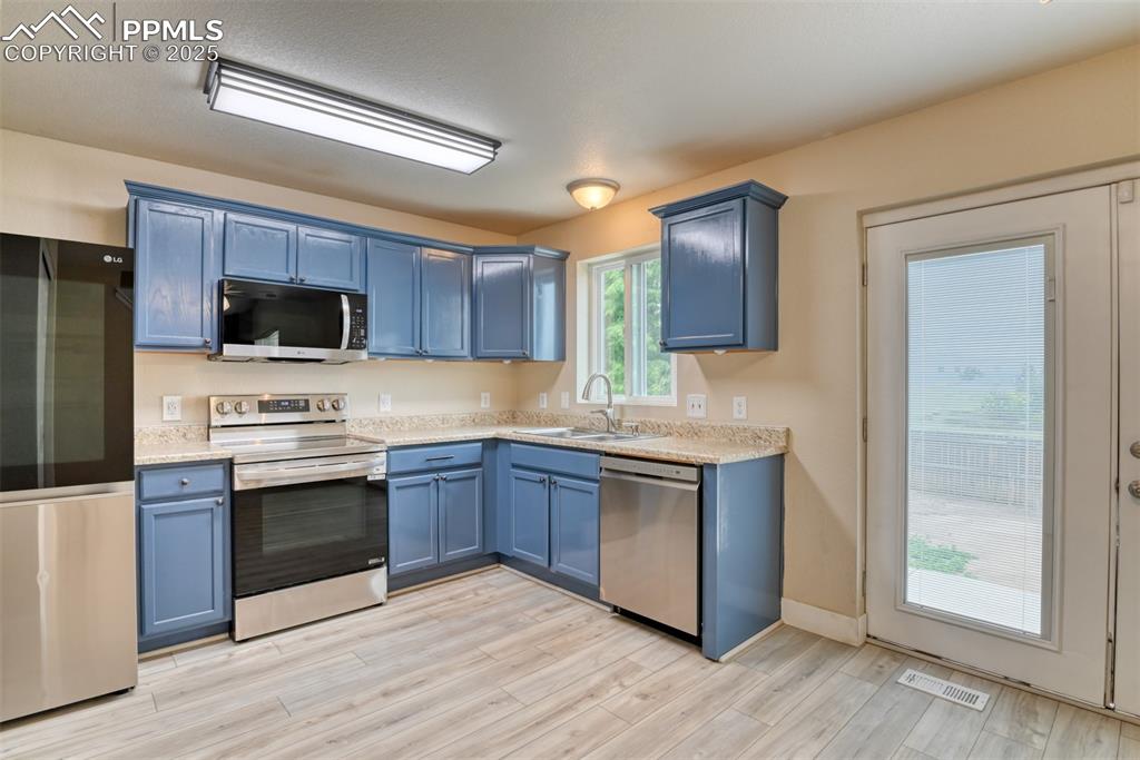 Image 7 of 21: Kitchen with stainless steel appliances, blue cabinets, and light wood-styl