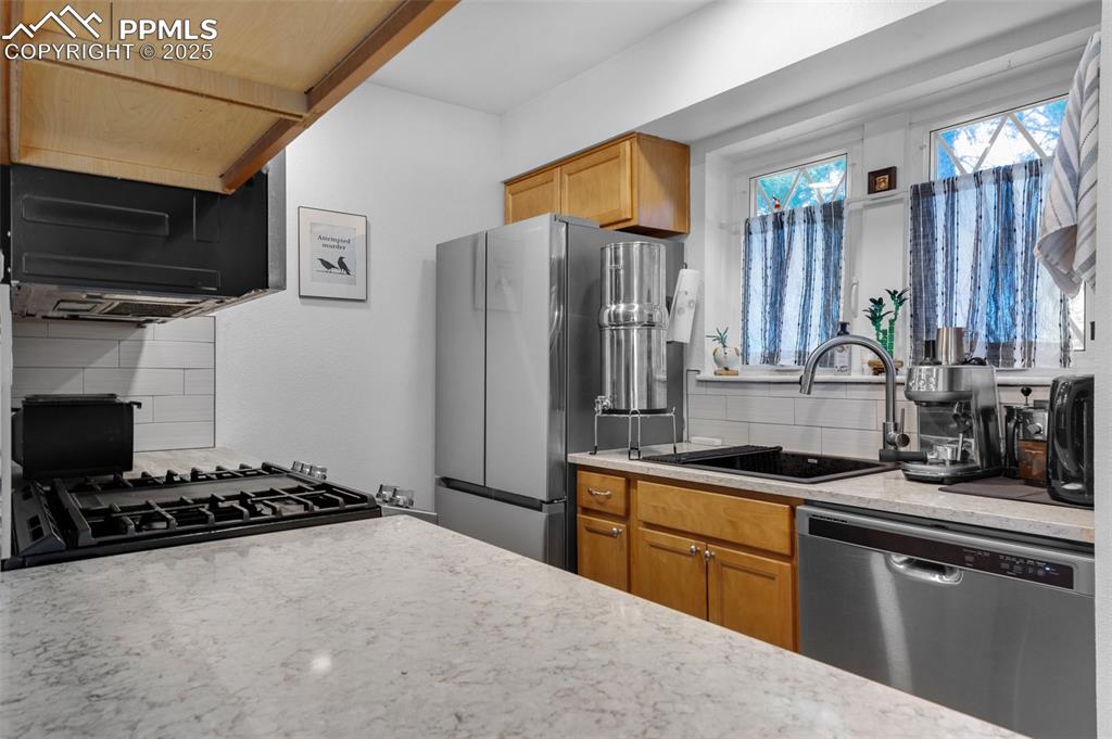 Image 11 of 26: Kitchen featuring appliances with stainless steel finishes, wood cabinetry,