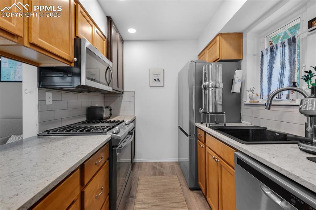 Image 12 of 26: Kitchen with appliances with stainless steel finishes, wood cabinets, backs