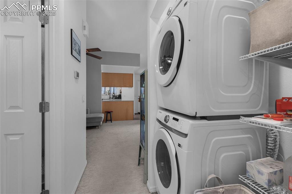 Image 21 of 26: Laundry area featuring stacked washer / drying machine and light colored ca