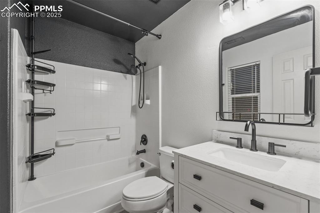 Image 13 of 20: Full bathroom with a textured wall, vanity, and washtub / shower combinatio