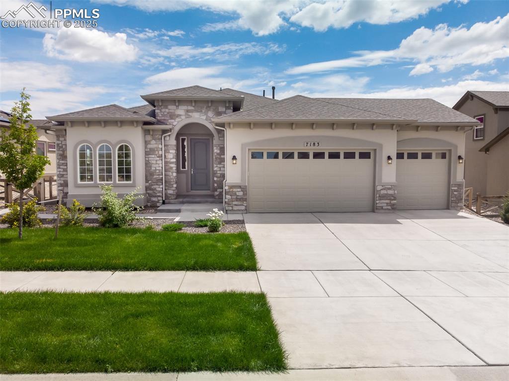 Caption: Mediterranean / spanish-style house with an attached garage, stone siding, driveway, stucco siding, 