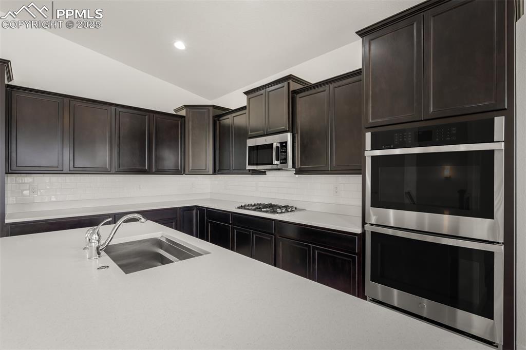 Image 17 of 46: Kitchen featuring vaulted ceiling, stainless steel appliances, light counte