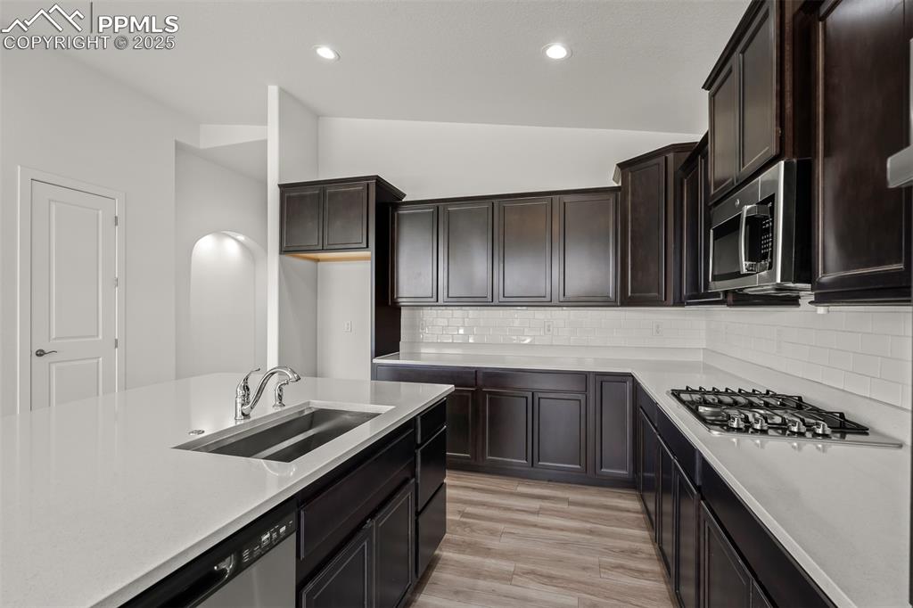 Image 18 of 46: Kitchen with vaulted ceiling, light countertops, light wood finished floors