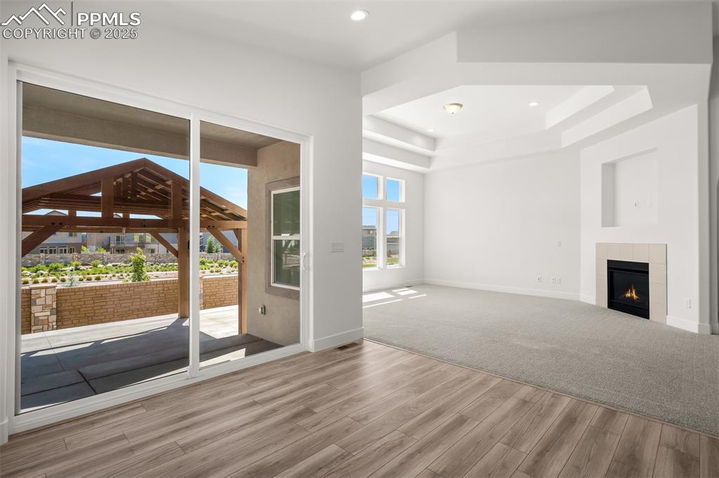 Image 21 of 46: Unfurnished living room with a raised ceiling, wood finished floors, a fire
