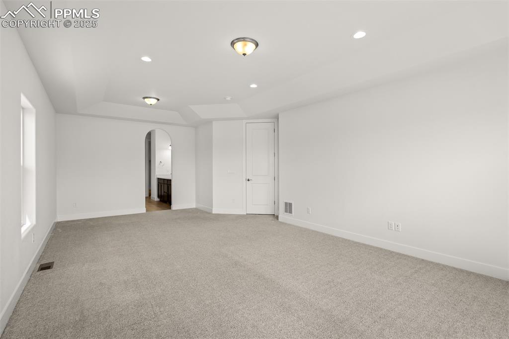Image 26 of 46: Unfurnished bedroom with arched walkways, light carpet, recessed lighting,