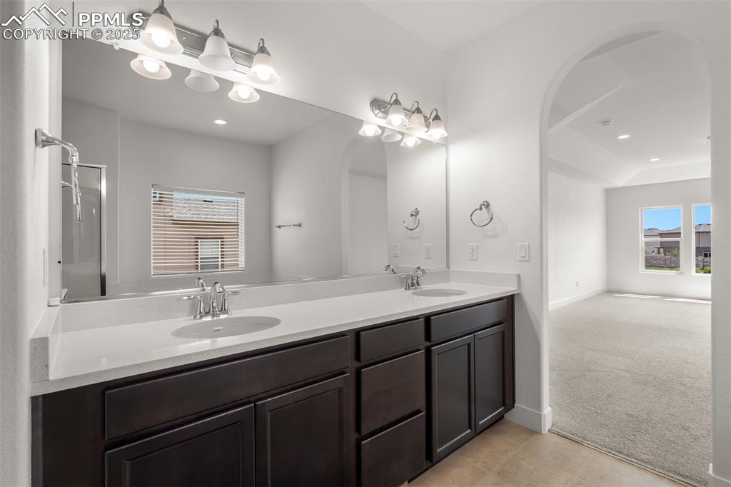 Image 28 of 46: Bathroom with double vanity, recessed lighting, a shower, and tile patterne