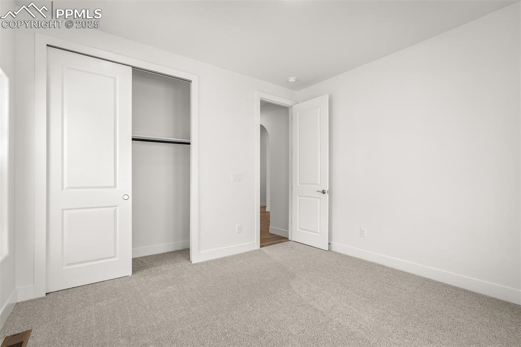 Image 35 of 46: Unfurnished bedroom featuring carpet flooring, arched walkways, and a close