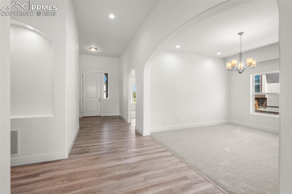 Image 37 of 46: Entrance foyer featuring arched walkways, light wood-style floors, a chande