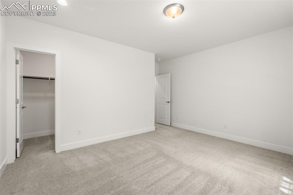 Image 42 of 46: Unfurnished bedroom featuring light carpet and a walk in closet