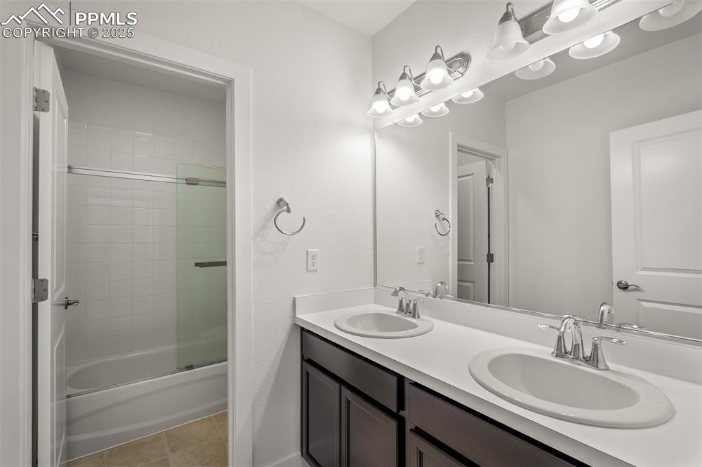 Image 43 of 46: Bathroom with double vanity, enclosed tub / shower combo, and tile patterne