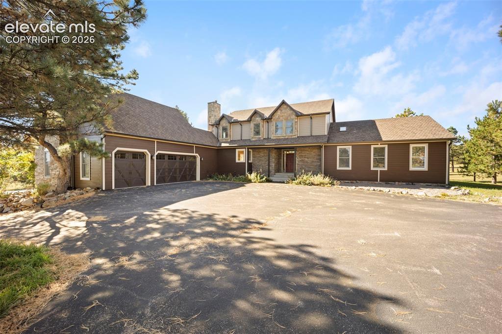 Image 1 of 40: Expansive paved driveway leading to a multi-level residence featuring stone