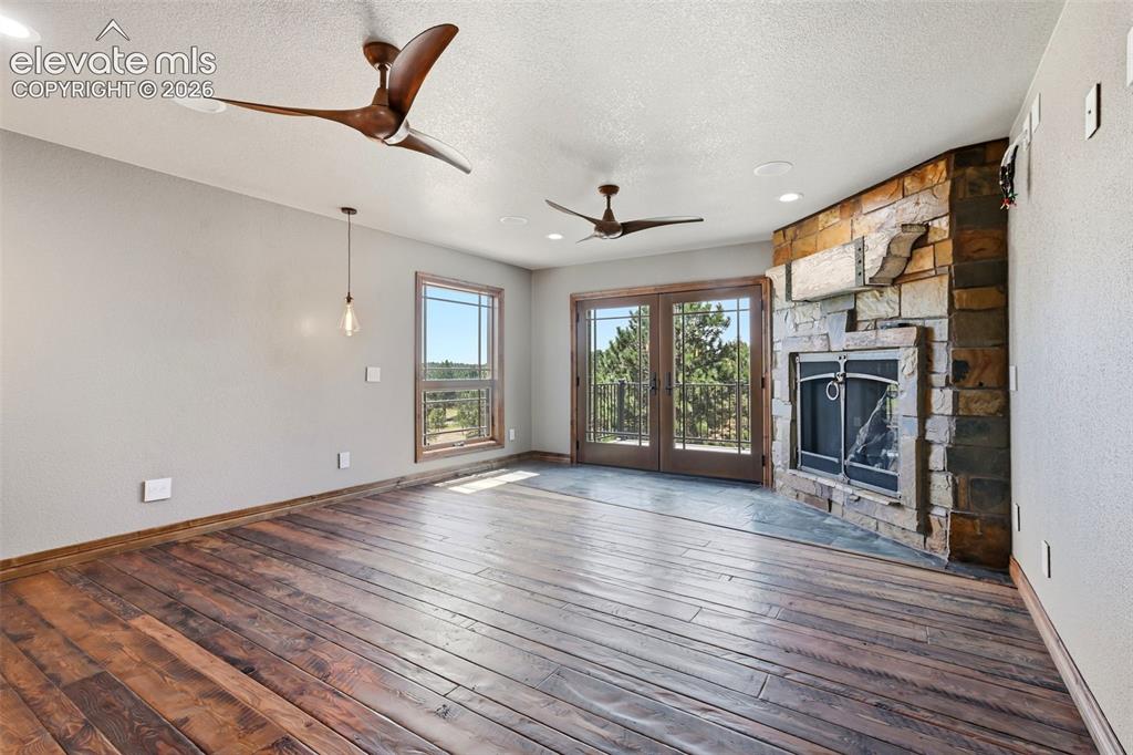 Image 15 of 40: Spacious interior featuring wide-plank wood flooring and a corner fireplace